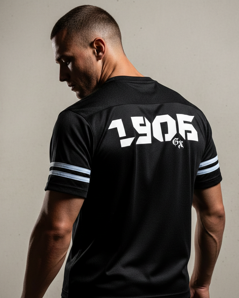 Man wearing a black sports jersey with '1906' printed on the back against a neutral background